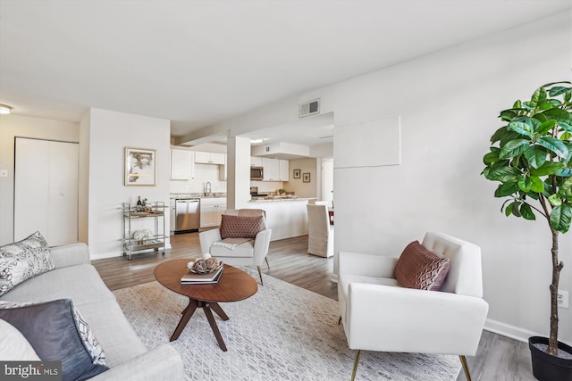 living area featuring wood finished floors, visible vents, and baseboards