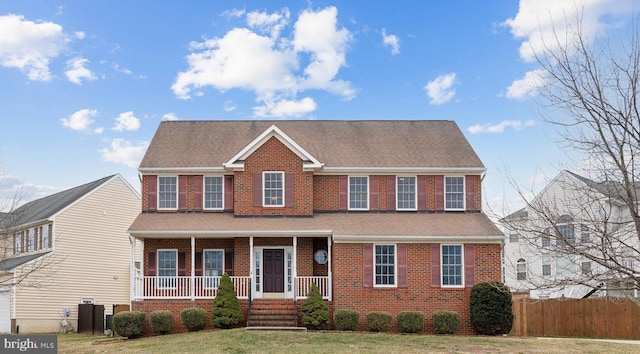 colonial home with covered porch and a front lawn