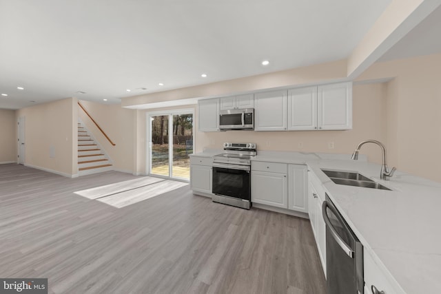 kitchen featuring light wood-style flooring, a sink, recessed lighting, stainless steel appliances, and white cabinets