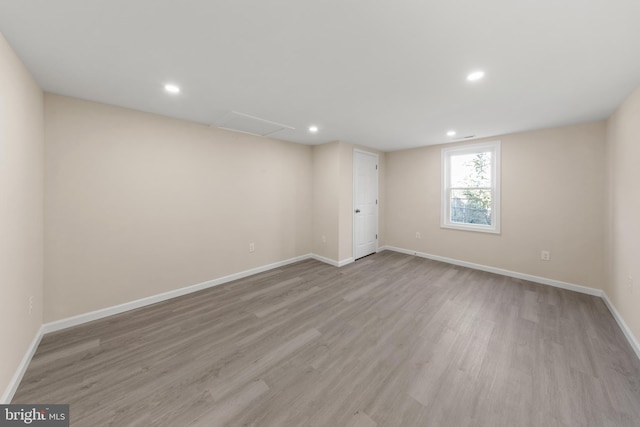 spare room with recessed lighting, baseboards, attic access, and wood finished floors