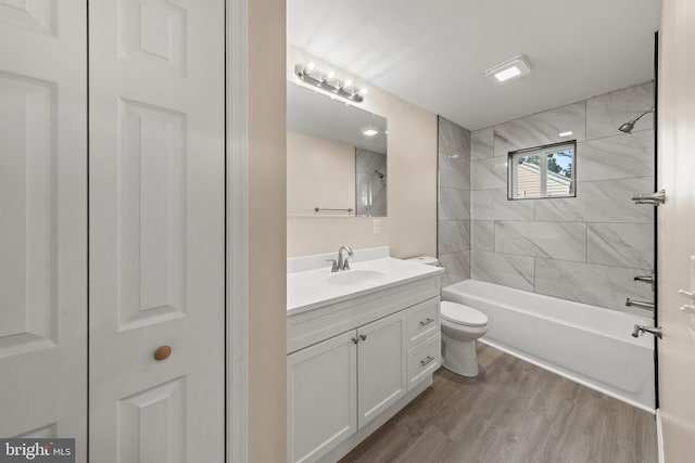 bathroom featuring vanity, toilet, wood finished floors, and tub / shower combination