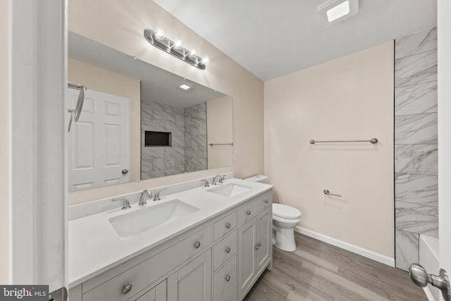 full bathroom with double vanity, wood finished floors, walk in shower, and a sink