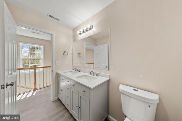 bathroom featuring visible vents, toilet, wood finished floors, and a sink