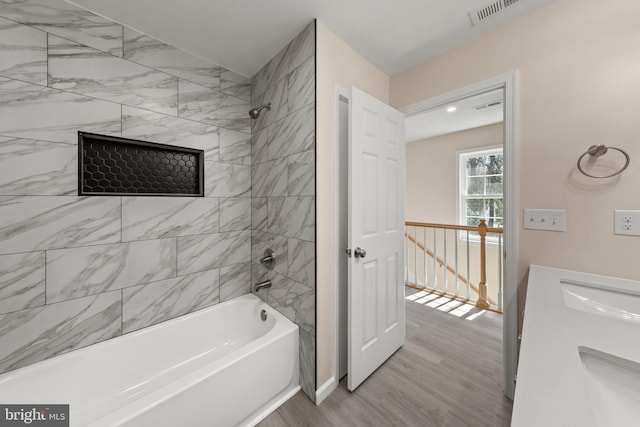 bathroom with visible vents, a sink, bathing tub / shower combination, and wood finished floors