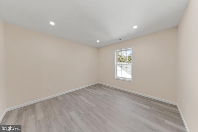 spare room featuring recessed lighting, baseboards, and light wood finished floors