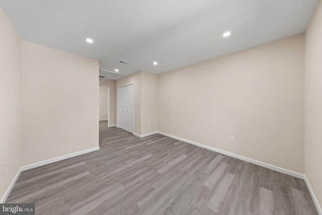 empty room featuring recessed lighting, attic access, baseboards, and wood finished floors