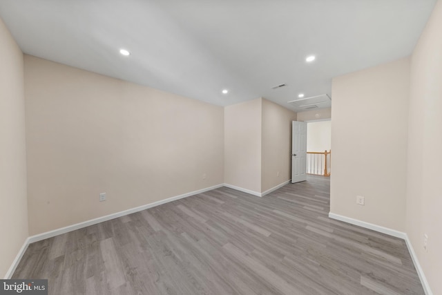 spare room featuring recessed lighting, attic access, baseboards, and wood finished floors