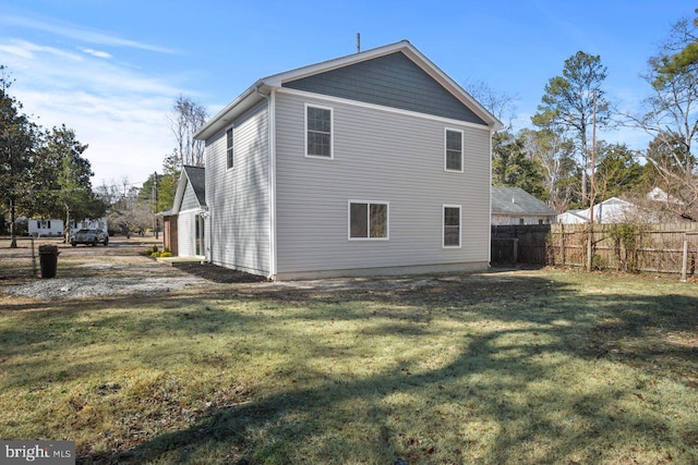 back of house featuring a lawn and fence