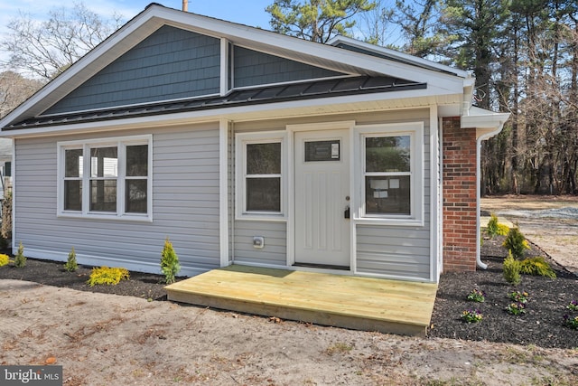 exterior space with a standing seam roof, brick siding, and metal roof