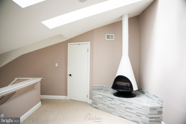 interior space featuring lofted ceiling with skylight and carpet flooring