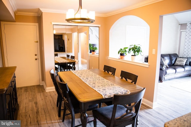 dining area with ornamental molding, light hardwood / wood-style floors, and an inviting chandelier