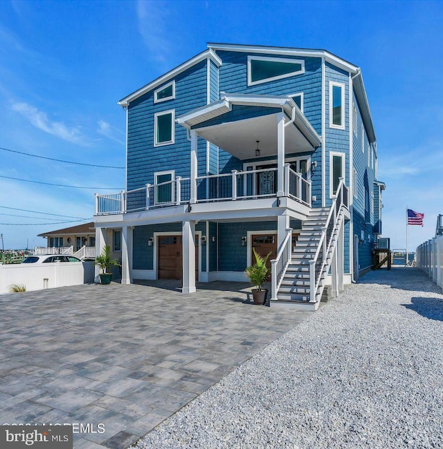 coastal home with a garage, decorative driveway, and stairs