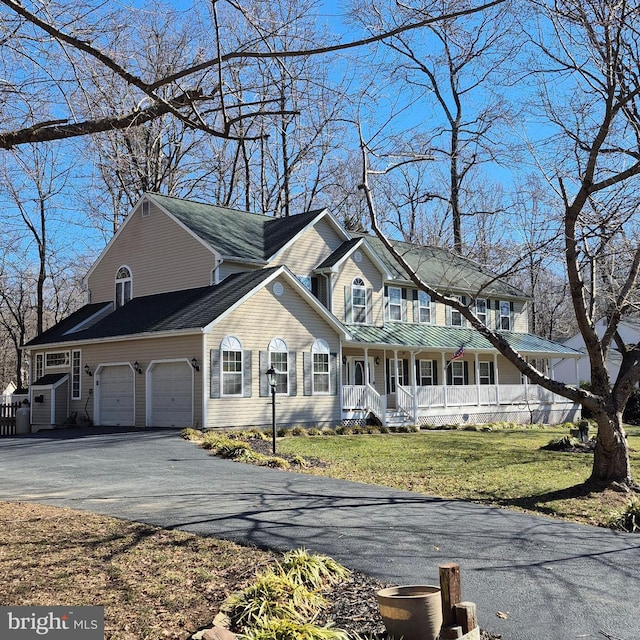 view of front of home with covered porch, a garage, and a front lawn