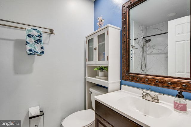 bathroom featuring toilet, vanity, and tiled shower