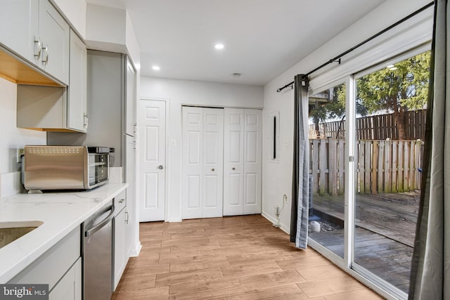 kitchen featuring light hardwood / wood-style floors, white cabinetry, dishwasher, and light stone countertops