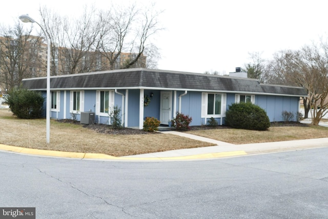 single story home with roof with shingles, a front yard, central AC unit, mansard roof, and a chimney