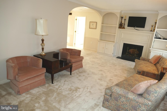 living room featuring built in features, carpet, a fireplace with flush hearth, arched walkways, and ornamental molding