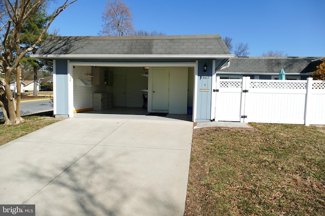 exterior space featuring a gate, fence, driveway, a shingled roof, and a lawn