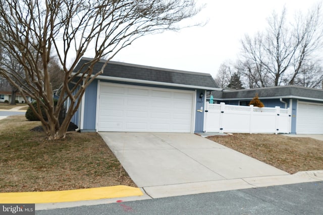 garage with concrete driveway, a gate, and fence