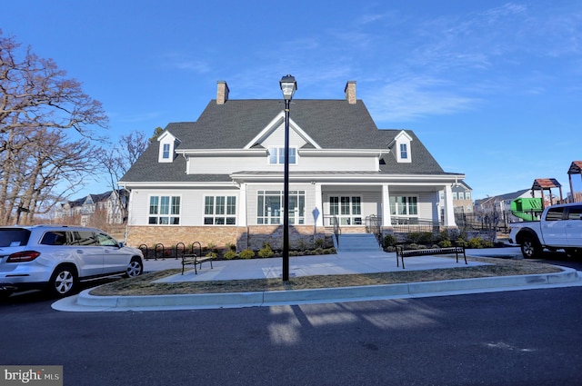 exterior space featuring stone siding, a porch, and a shingled roof