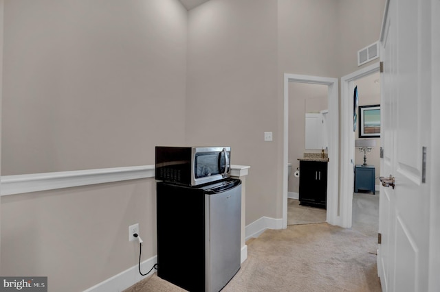 home office featuring light carpet, baseboards, a towering ceiling, and visible vents