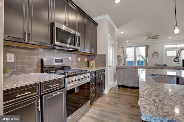 kitchen with open floor plan, stainless steel appliances, dark brown cabinetry, and crown molding