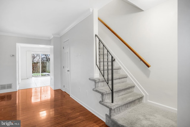 stairs with hardwood / wood-style flooring and crown molding