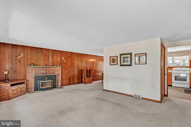 unfurnished living room with baseboards, visible vents, wooden walls, and carpet flooring