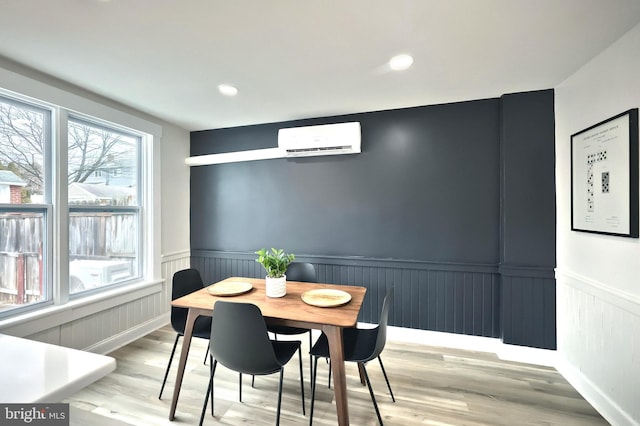 dining space featuring a wall mounted AC and light wood-type flooring