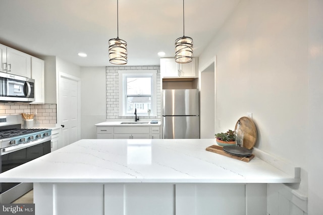 kitchen with sink, decorative light fixtures, appliances with stainless steel finishes, decorative backsplash, and white cabinets