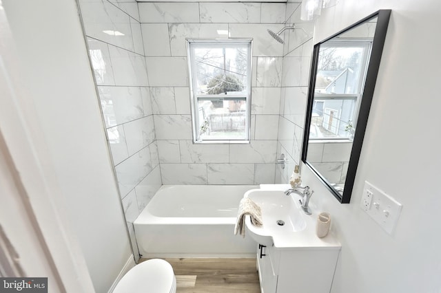 full bathroom with tiled shower / bath combo, vanity, a healthy amount of sunlight, and toilet