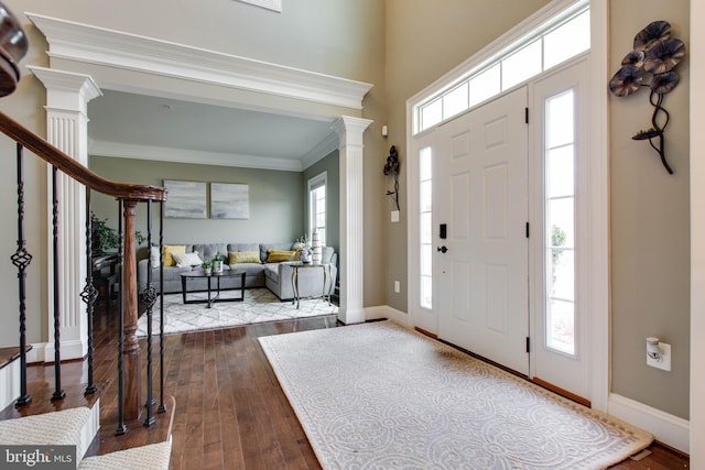 entryway with wood-type flooring, ornate columns, and ornamental molding