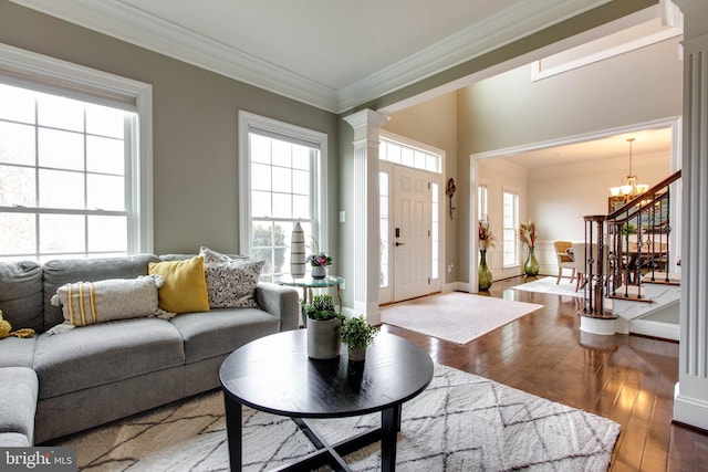 living room featuring hardwood / wood-style floors, a wealth of natural light, crown molding, and decorative columns