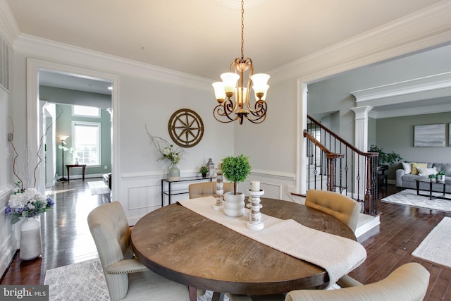 dining room with ornate columns, a chandelier, crown molding, and dark hardwood / wood-style floors