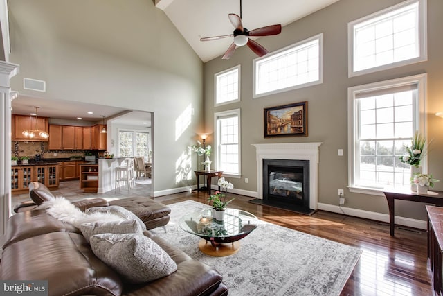 living room featuring hardwood / wood-style floors, high vaulted ceiling, and ceiling fan