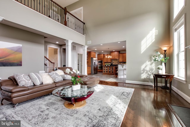 living room with dark hardwood / wood-style flooring, decorative columns, and a high ceiling