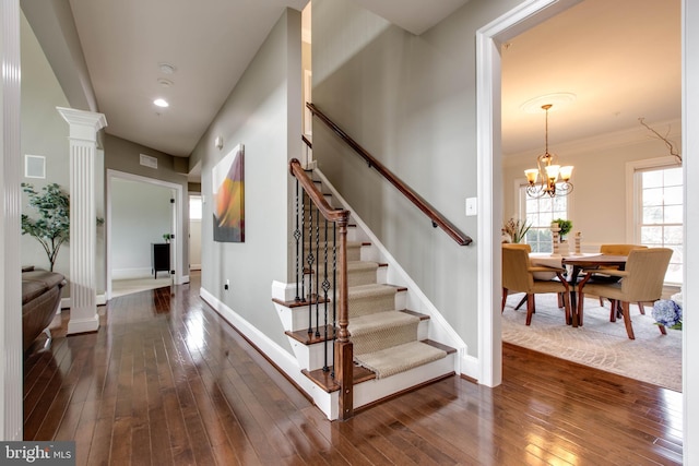 stairway featuring decorative columns, an inviting chandelier, and wood-type flooring