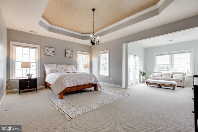 carpeted bedroom featuring a tray ceiling, ornamental molding, multiple windows, and an inviting chandelier