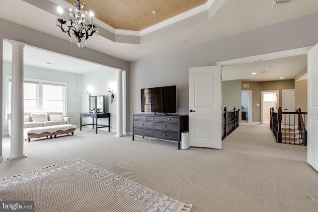 carpeted living room with ornamental molding, ornate columns, a notable chandelier, and a raised ceiling