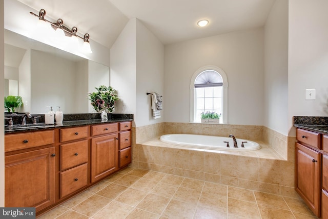 bathroom with tile patterned floors, vanity, and a relaxing tiled tub