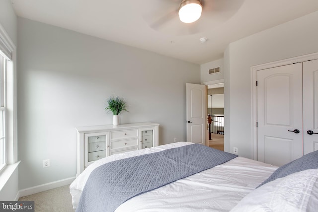 bedroom with a closet, light colored carpet, and ceiling fan