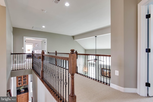 hallway with carpet, vaulted ceiling, and plenty of natural light