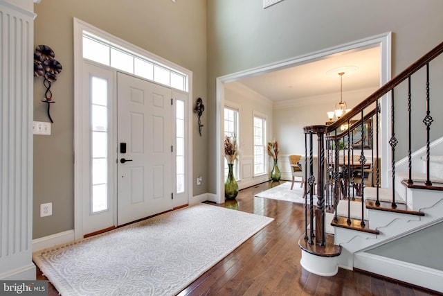 entrance foyer with a notable chandelier, crown molding, and dark hardwood / wood-style floors