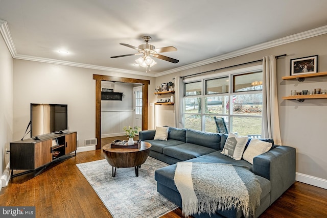 living area featuring baseboards, visible vents, dark wood finished floors, ceiling fan, and crown molding