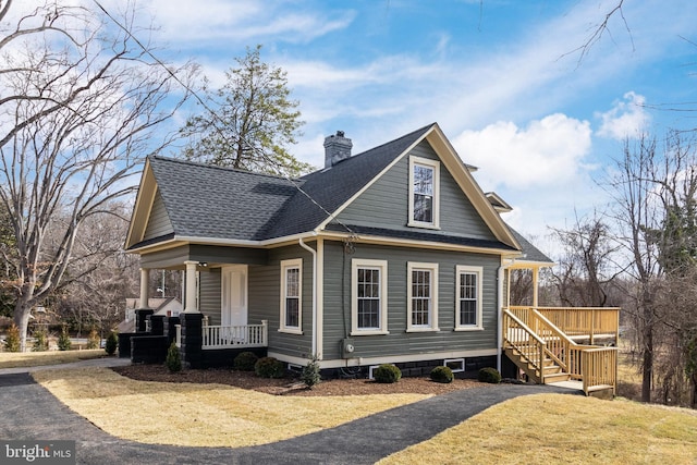 view of front facade featuring roof with shingles, a porch, and a chimney