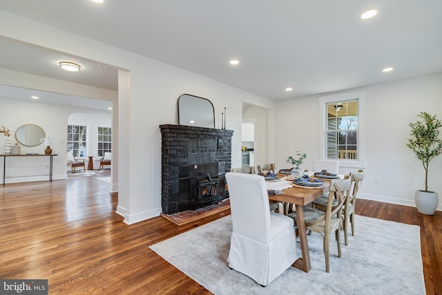 dining space with arched walkways, recessed lighting, baseboards, and wood finished floors