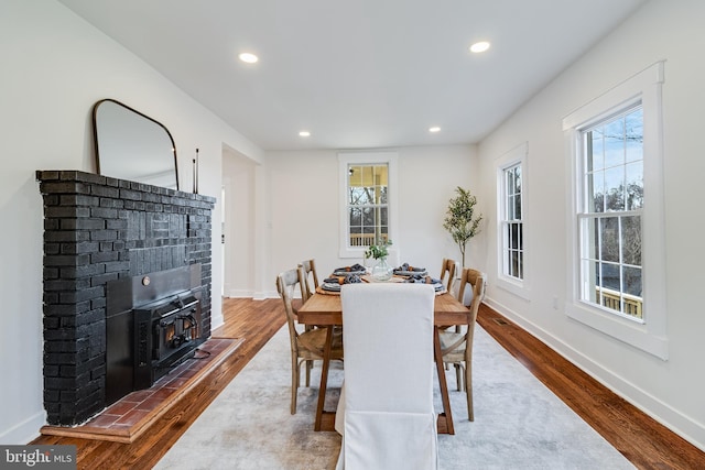 dining space with recessed lighting, baseboards, wood finished floors, and a wood stove