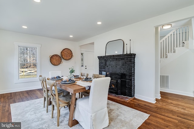 dining room featuring visible vents, wood finished floors, stairway, a fireplace, and baseboards