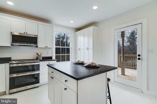 kitchen with a kitchen island, recessed lighting, white cabinets, appliances with stainless steel finishes, and dark countertops