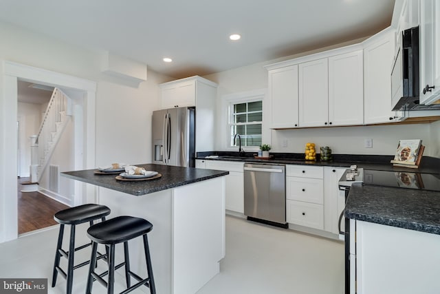 kitchen with a breakfast bar, a center island, white cabinetry, recessed lighting, and appliances with stainless steel finishes